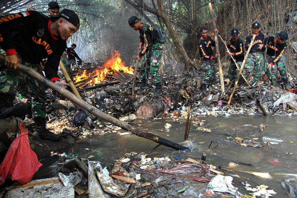 Sejumlah anggota Yonif 315/Garuda Bogor membersihkan sampah yang menghambat aliran air Cisadane, Kalibaru Barat, Cilebut, Kabupaten Bogor, Jawa Barat.