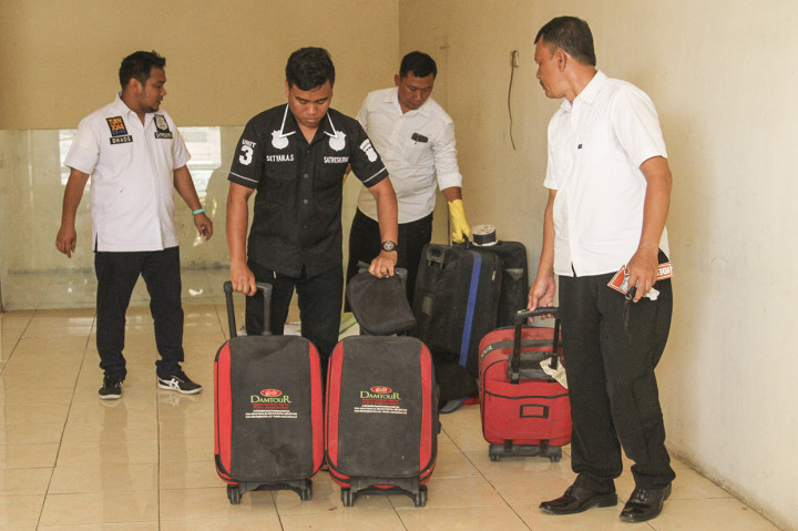 Petugas kepolisian mengambil barang bukti koper milik PT Damtour di Depok, Jawa Barat.