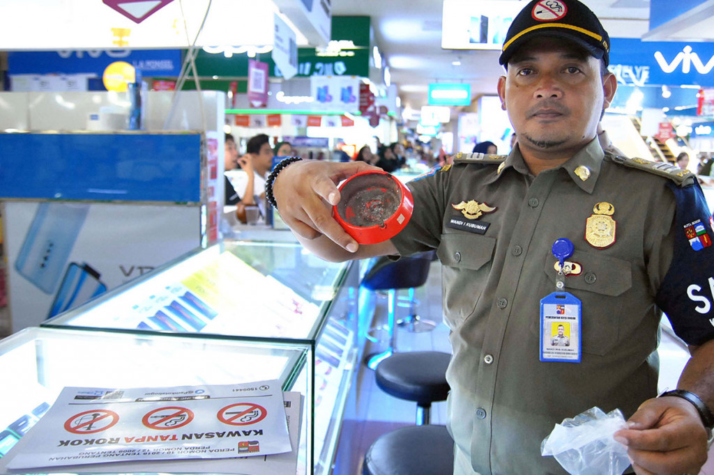 Anggota Satgas Peraturan Daerah (Perda) Kawasan Tanpa Rokok (KTR) menunjukkan barang bukti asbak rokok saat razia dan sidang tindak pidana ringan (Tipiring) di Mall BTM, Kota Bogor, Jawa Barat.