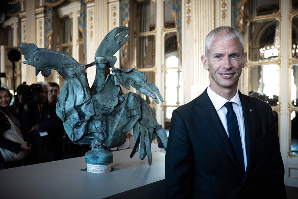 Menteri Kebudayaan Prancis Franck Riester berdiri di sebelah ayam jantan yang sebelumnya duduk di puncak menara Katedral Notre-Dame, selama presentasi pameran 'Revoir Notre-Dame de Paris' (Untuk melihat lagi Notre-Dame de Paris), di Paris, pada Jumat, 20 September 2019 waktu setempat. 
