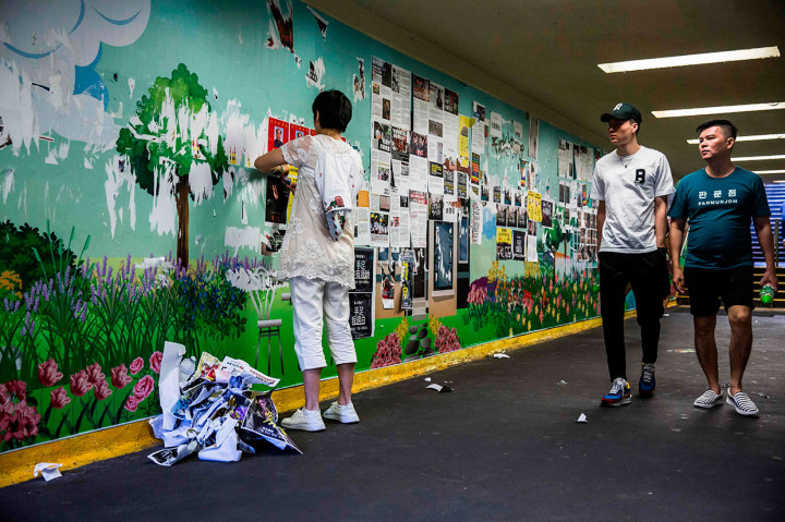 Seorang wanita mencopoti poster yang dipasang oleh demonstran anti-pemerintah sebagai bagian dari Lennon Walls di distrik Mong kok, Hong Kong pada Sabtu, 21 September 2019.
