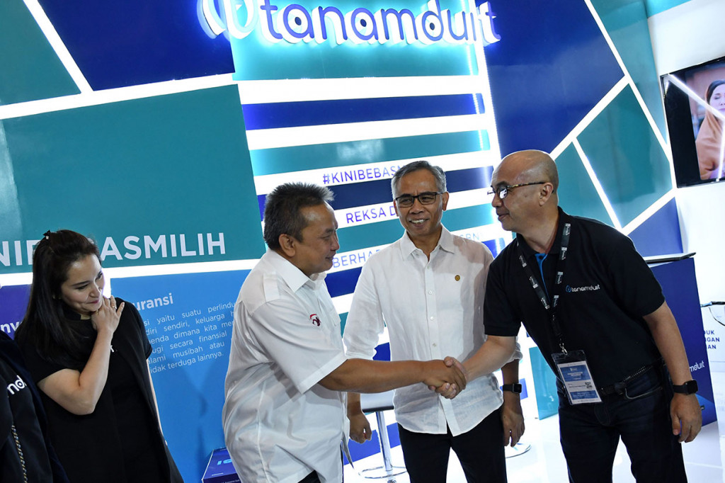 Ketua Dewan Komisioner Otoritas Jasa Keuangan (OJK) Wimboh Santoso (kedua kanan) dan Kepala Eksekutif Pengawas Pasar Modal OJK Hoesen (kedua kiri), disambut Chief Business Tanamduit M. Hanif (kanan) dan Co Founder Rini Hapsari saat meninjau stan Tanamduit pada pameran Indonesia Fintech Summit & Expo 2019 di Jakarta Convention Center (JCC), Jakarta.