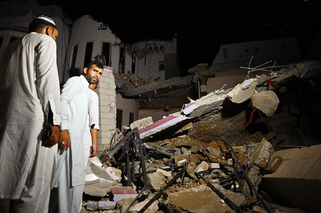 Warga berdiri di dekat bangunan yang runtuh akibat diguncang gempa di pinggiran Mirpur, Pakistan, Selasa, 24 September 2019.