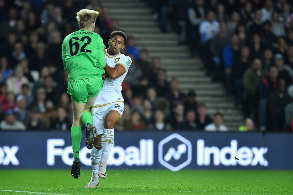 Penjaga gawang Liverpool Caoimhin Kelleher bertabrakan dengan Sam Nombe saat berusaha mengamankan gawangnya dari serbuan pemain-pemain Dons.