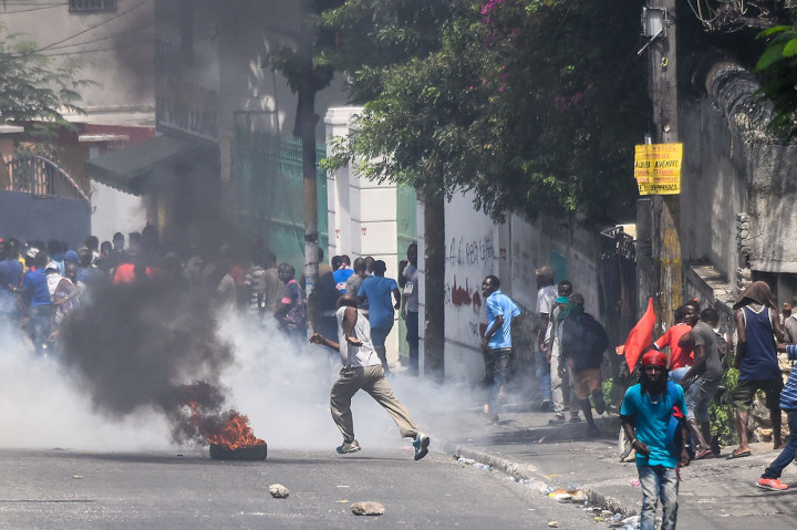 Para pengunjuk rasa berlarian menghindari tembakan gas air mata yang dilontarkan petugas kepolisian di Port-Au-Prince, Haiti, Jumat, 27 September 2019 waktu setempat.