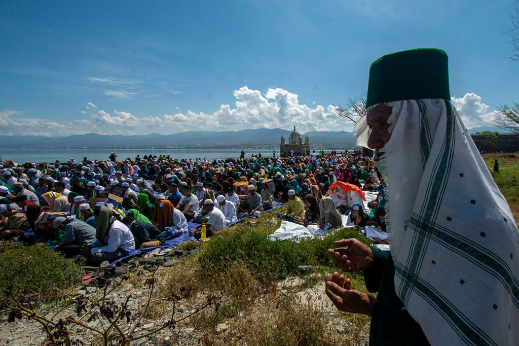 Puluhan warga berdoa pada zikir bersama di depan Masjid Arqam Baburrahman yang amblas ke laut di Pantai Kampung Lere, Palu, Sulawesi Tengah, Sabtu, 28 September 2019.