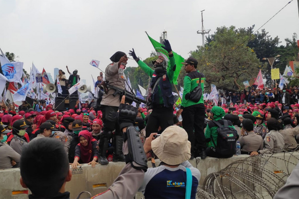 Selain berorasi, massa buruh juga banyak menyanyikan lagu-lagu perjuangan melalui pengeras suara. Mereka joget bareng dengan para aparat kepolian yang berjaga.