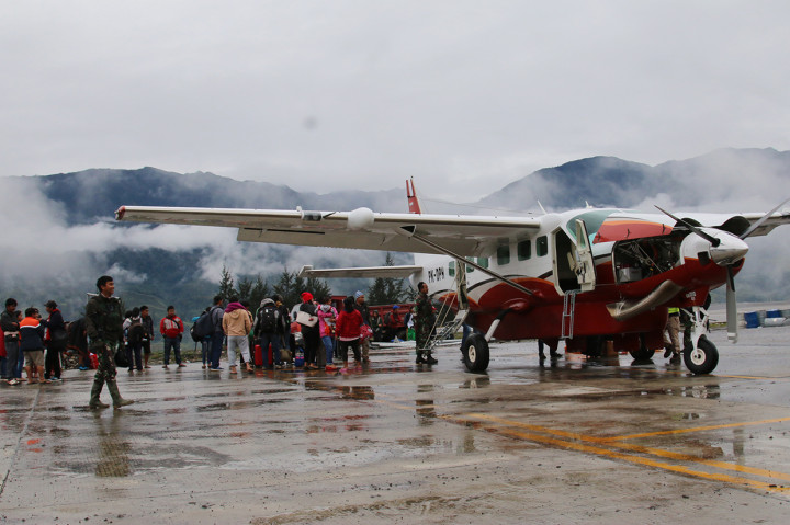 Warga menunggu pesawat dengan penjagaan aparat keamanan di Bandara Ilaga, Kabupaten Puncak, Papua.

