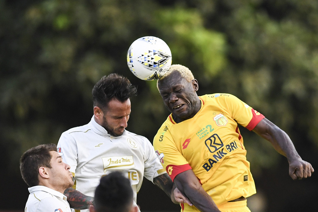 Pesepak bola Bhayangkara FC Herman Dzumafo Epandi (kanan) berebut bola di udara dengan pesepak bola PSS Sleman Alfonso De La Cruz (kiri) saat laga lanjutan Liga 1 di Stadion PTIK, Jakarta.