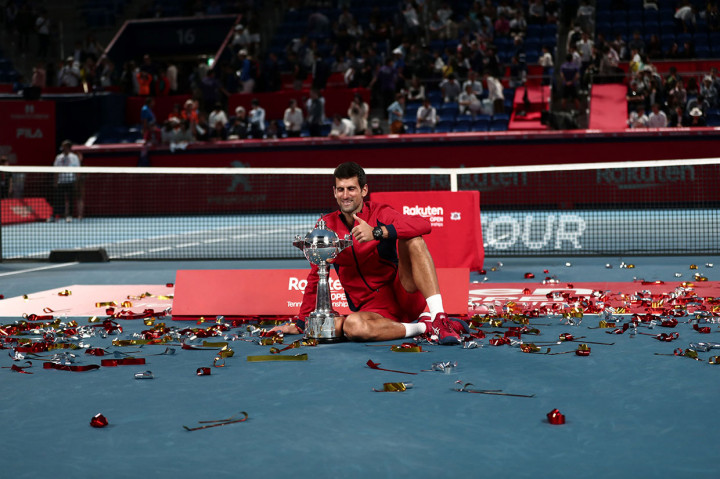 Petenis Serbia Novak Djokovic duduk di tengah lapangan sembari memamerkan trofi Jepang Terbuka 2019 yang baru saja dia raih, Minggu, 6 Oktober 2019.