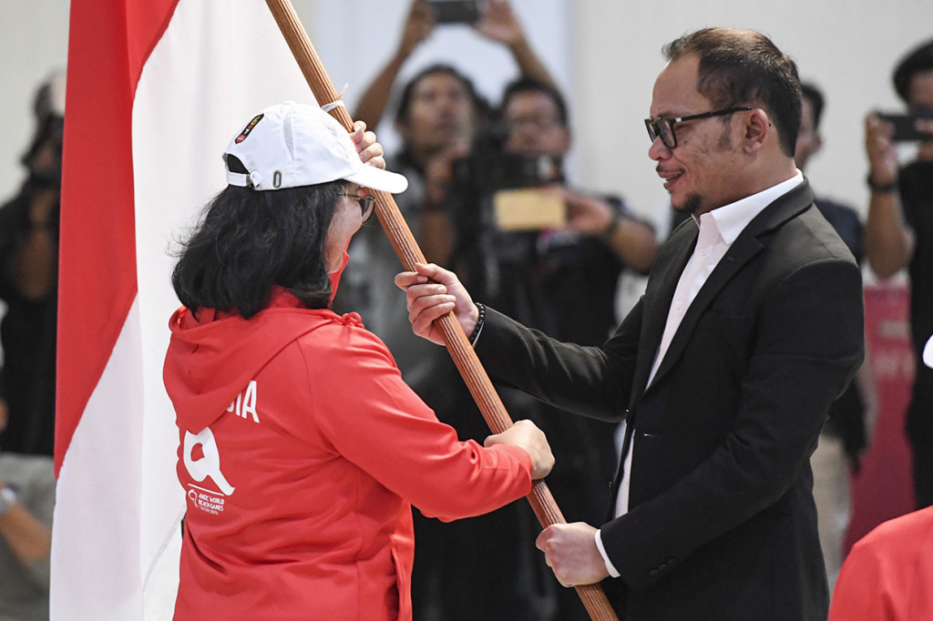 Plt Menteri Pemuda dan Olahraga Hanif Dhakiri (kanan) menyerahkan bendera Merah Putih kepada CdM Kontingen Indonesia Hellen Sarita de Lima (kiri) saat upacara pengukuhan dan pelepasan kontingen World Beach Games 1 2019 di Kemenpora, Jakarta.