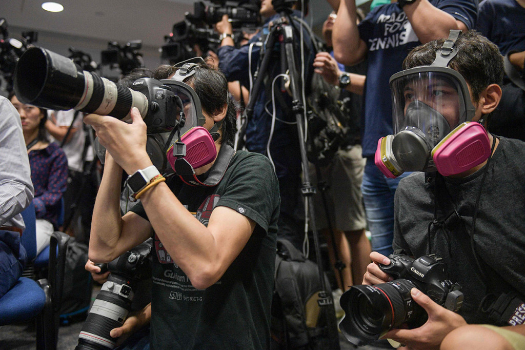 Wartawan menggunakan masker pelindung saat menghadiri konferensi pers polisi di Hong Kong. AFP Photo/Nicolas Asfouri