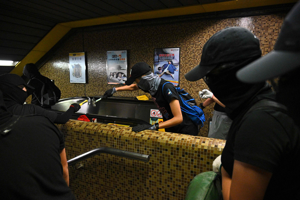 Sekelompok pemrotes bermasker menghancurkan stasiun MTR Wong Tai Sin di distrik Kowloon Hong Kong. AFP Photo/Philip Fong
