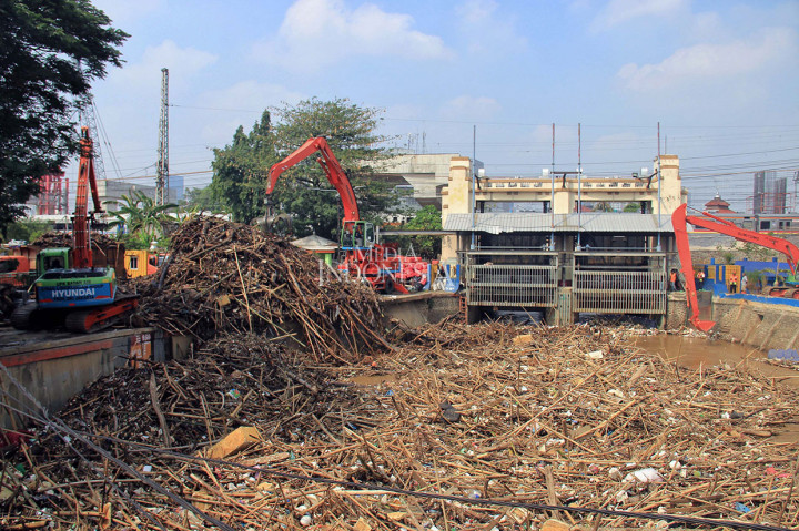 Pekerja UPK Badan Air Dinas Lingkungan Hidup DKI Jakarta menggunakan alat berat membersihkan sampah yang menumpuk di Pintu Air Manggarai, Jalan Tambak, Kecamatan Menteng, Jakarta Pusat, Rabu, 9 Oktober 2019.