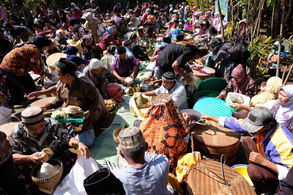 Sejumlah warga membagikan makanan kepada pengunjung saat tradisi Nyadran Ngropoh di komplek makam Desa Ngropoh, Kranggan, Temanggung, Jawa Tengah.