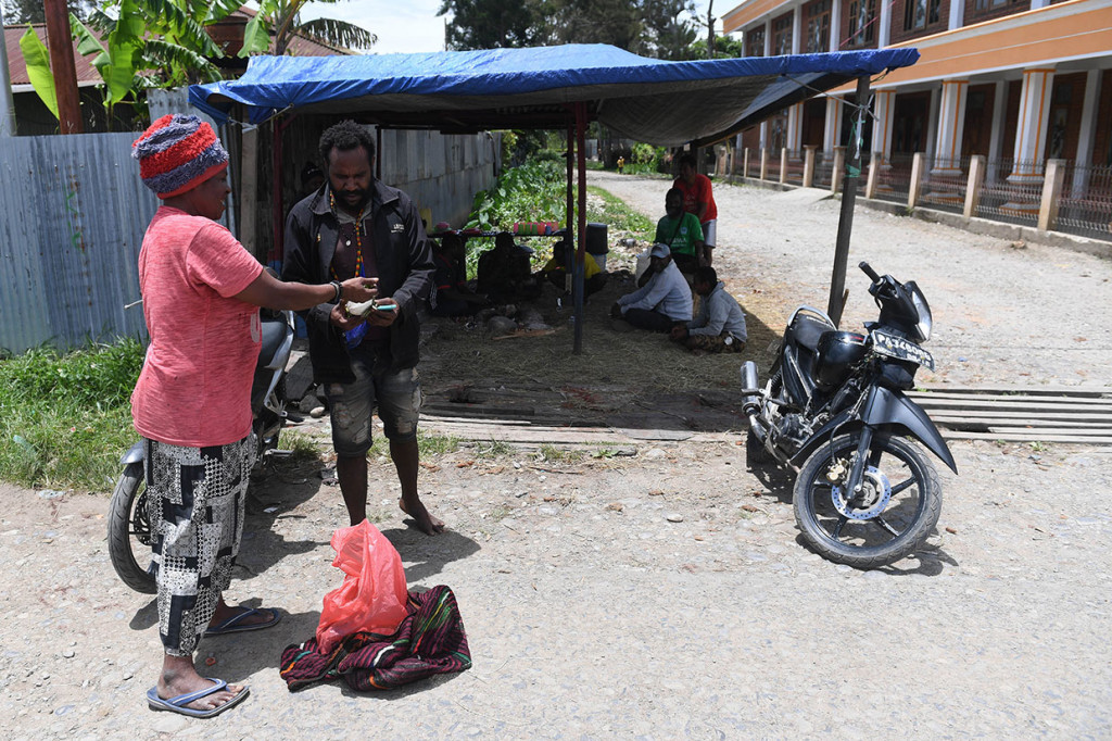 Seorang perempuan memberikan pinang pada salah satu warga yang berjaga di posko keamanan di Desa Honelama 2, Kota Wamena, Kabupaten Jayawijaya, Papua, Sabtu, 12 Oktober 2019.