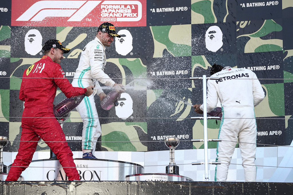 Pemenang F1 GP Jepang Valtteri Bottas (tengah) bersama peringkat kedua Sebastian Vettel (kiri) menyemprotkan sampanye ke pembalap Mercedes asal Inggris Lewis Hamilton saat di atas podium di Suzuka, Minggu, 13 Oktober 2019.