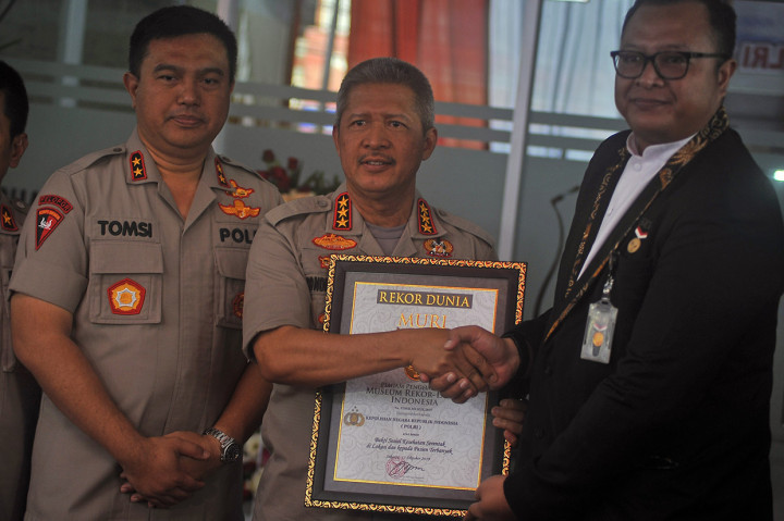 Kabaharkam Polri Komjen Pol Condro Kirono (tengah) didampingi Kapolda Banten Irjen Pol Tomsi Tohir (kiri) menerima piagam penghargaan untuk kegiatan Bakti Sosial Polri secara serentak dengan pasien terbanyak dari Manajer MURI Awan Raharjo (kanan) di Serang, Banten.
