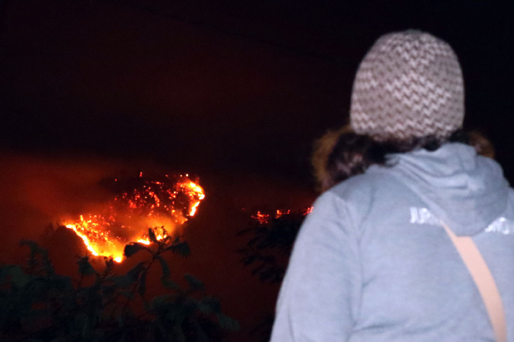 Warga menyaksikan kebakaran hutan Gunung Ranti yang terlihat dari Tawonan, Banyuwangi, Jawa Timur. Kebakaran hutan tersebut menyebabkan jalur pendakian Gunung Ijen ditutup sementara. 