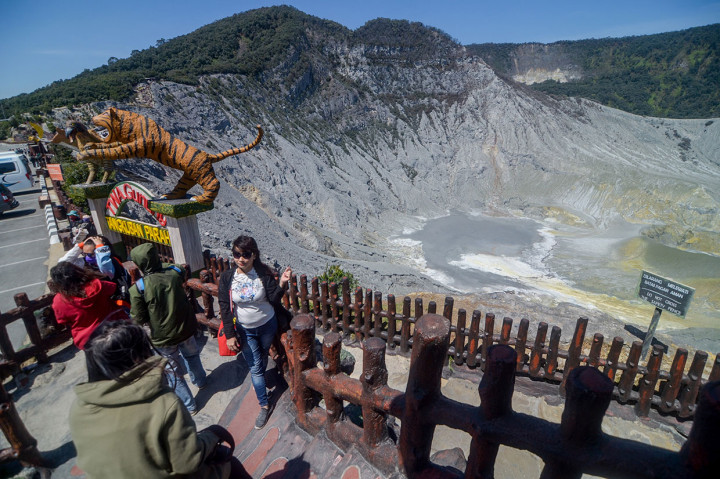 Pengunjung berfoto dengan latar belakang kawah Gunung Tangkuban Parahu di Kabupaten Subang, Jawa Barat, Selasa, 22 Oktober 2019.