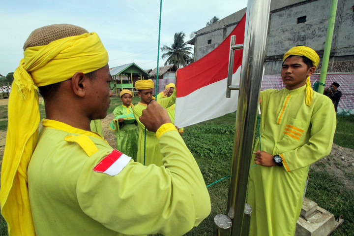 Santri Tarbiyah Islamiah Mazhab Syafi'i mengibarkan bendera Merah Putih pada upacara peringatan Hari Santri Nasional (HSN) di lapangan balai pengajian Jamaah Tarbiah Islamiah, Kandang, Lhokseumawe, Aceh.