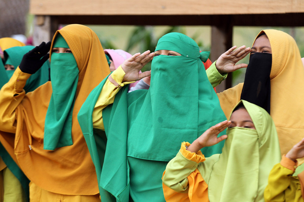 Santri Tarbiyah Islamiah Mazhab Syafi'i mengibarkan bendera Merah Putih pada upacara peringatan Hari Santri Nasional (HSN) di lapangan balai pengajian Jamaah Tarbiah Islamiah, Kandang, Lhokseumawe, Aceh.