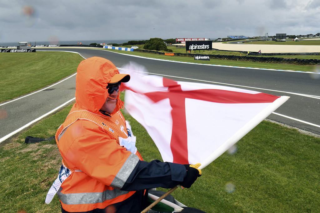 Petugas mengibarkan bendera kepada pengendara untuk menghentikan sesi latihan karena angin kencang dan hujan melanda Sirkuit Phillip Island, Sabtu, 26 Oktober 2019.