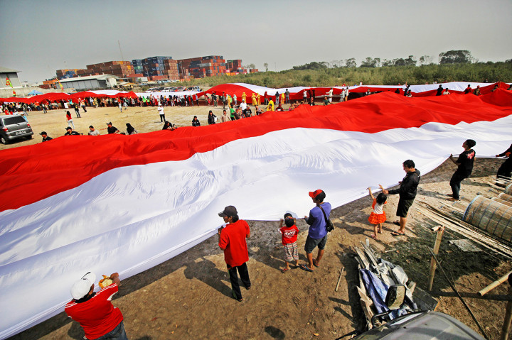 Warga membentangkan bendera Merah Putih saat memperingati Hari Sumpah Pemuda di kampung nelayan Greges, Surabaya, Jawa Timur.