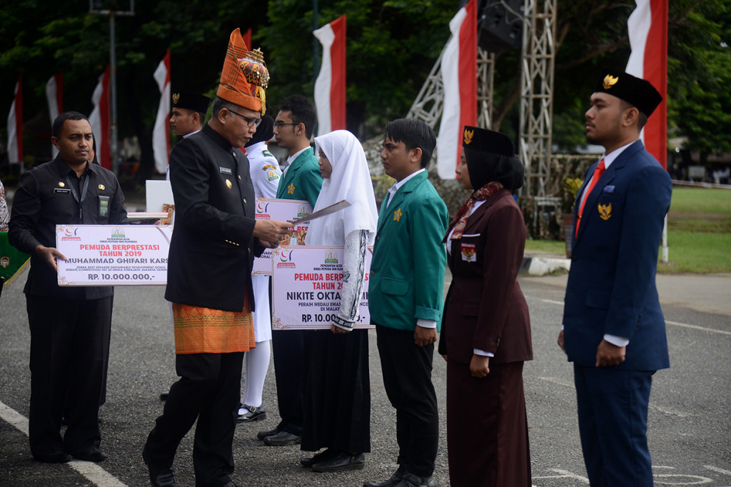 Plt Gubernur Aceh Nova Iriansyah (kedua kiri) memberikan penghargaan kepada sejumlah pemuda berprestasi tingkat nasional dan internasional saat upacara memperingati Hari Sumpah Pemuda di Lapangan Blang Padang, Banda Aceh, Acegh. Peringatan Hari Sumpah Pemuda di Aceh yang melibatkan ribuan pelajar, santri, TNI dan Polri dan Ormas Pemuda itu dimeriahkan dengan atraksi drama kolosal pahlawan Cut Nyak Dhien, Drum Band, Tablig Akbar dan Deklarasi Damai. Antara Foto/Ampelsa