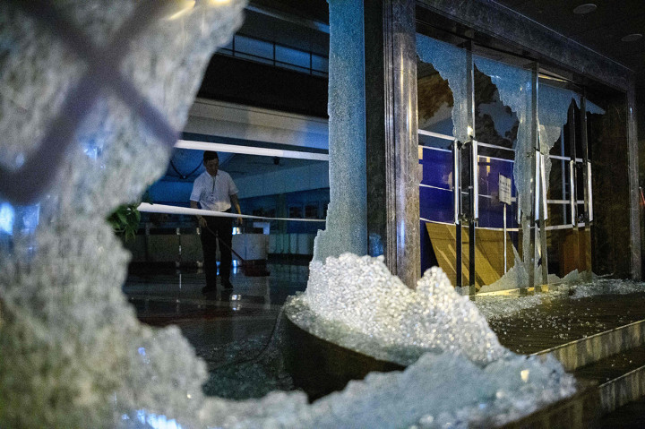 Beberapa staf kebersihan terlihat menyapu kaca yang berserakan di lantai melalui pintu dan jendela yang rusak. AFP Photo/Anthony Wallace