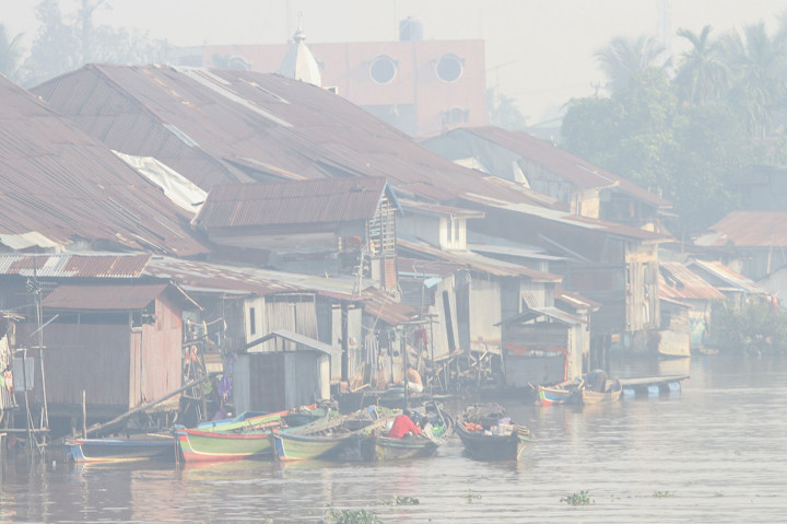 Warga beraktivitas di Sungai Martapura yang diselimuti kabut asap di Kota Banjarmasin, Kalimantan Selatan, Jumat, 8 November 2019.
