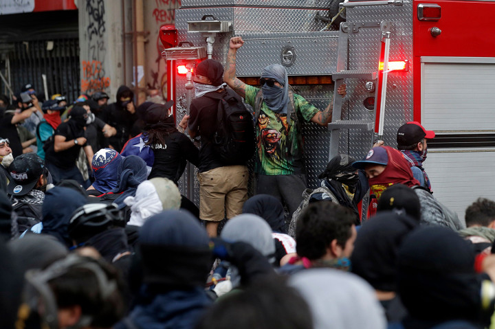 Sejumlah demonstran bentrok dengan polisi yang memasang barikade untuk melindungi gedung Universitas Pedro de Valdivia. AFP Photo/Javier Torres