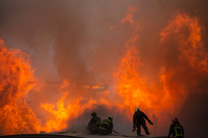 Petugas pemadam kebakaran berusaha memadamkan api yang membakar gedung universitas Pedro de Valdivia. AFP Photo/Claudio Reyes