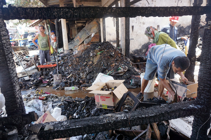 Pedagang mengais barang dagangan yang masih bisa diselamatkan di blok kios/tokonya yang hangus terbakar di Pasar Ngunut, Tulungagung, Jawa Timur.