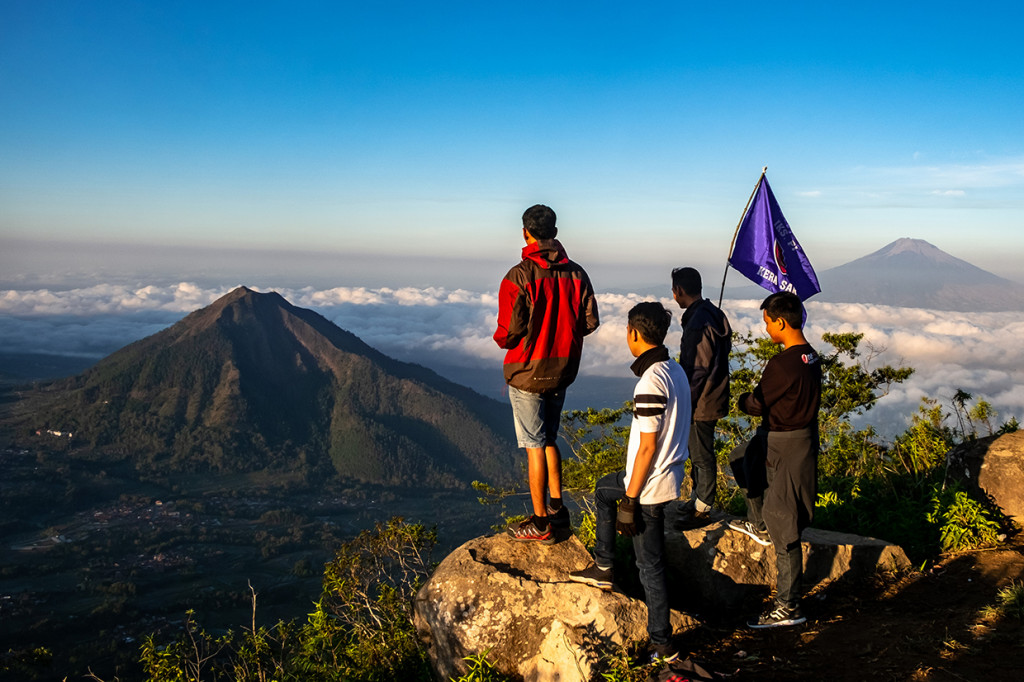 Sejumlah wisatawan menikmati pemandangan Gunung Merbabu (kiri) dan Gunung Andong (kanan) dari Gunung Telomoyo, Desa Sepakung, Banyubiru, Kabupaten Semarang, Jawa Tengah.