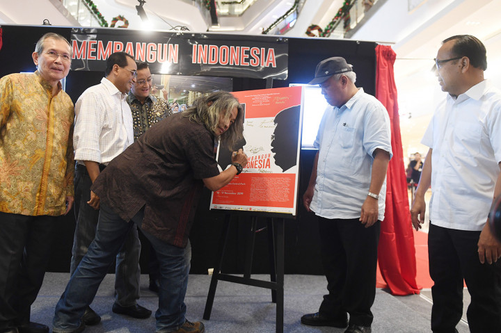 Kurator foto Oscar Motuloh (tengah) menandatangani poster disaksikan Mensesneg Pratikno (kanan), Menteri PUPR Basuki Hadimuljono (kedua kanan), Menteri Perhubungan Budi Karya Sumadi (kedua kiri), Menteri Sosial Juliari Batubara (ketiga kiri) serta Founder Agung Podomoro Land Trihatma Kusuma Haliman (kiri) saat acara pembukaan pameran foto Membangun Indonesia di Neo Soho, Jakarta.
