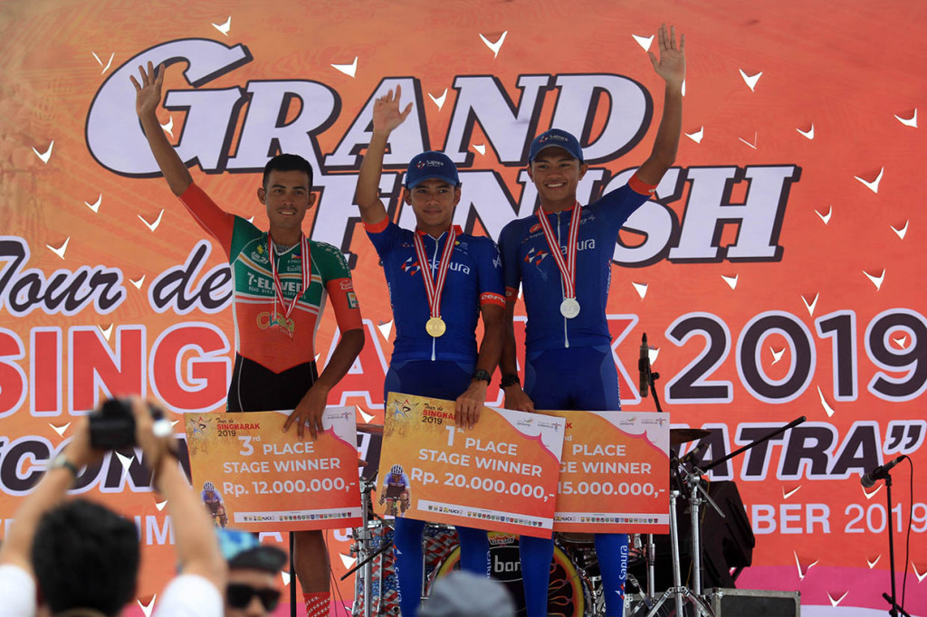 Pebalap Azman Muhammad Zawawi (tengah), Mohd Zarif Muhammad Nur Aiman (kanan) dan Felipe Marcelo (kiri) mengangkat tangannya setelah menerima hadiah sebagai pemenang etape kesembilan Tour De Singkarak 2019 di Padang, Sumatera Barat. Antara Foto/Muhammad Arif Pribadi