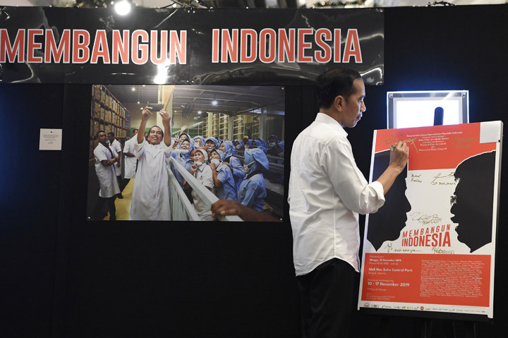 Presiden Joko Widodo menandatangani poster pameran fotografi Membangun Indonesia di Atrium Neo Soho Mall, Jakarta.