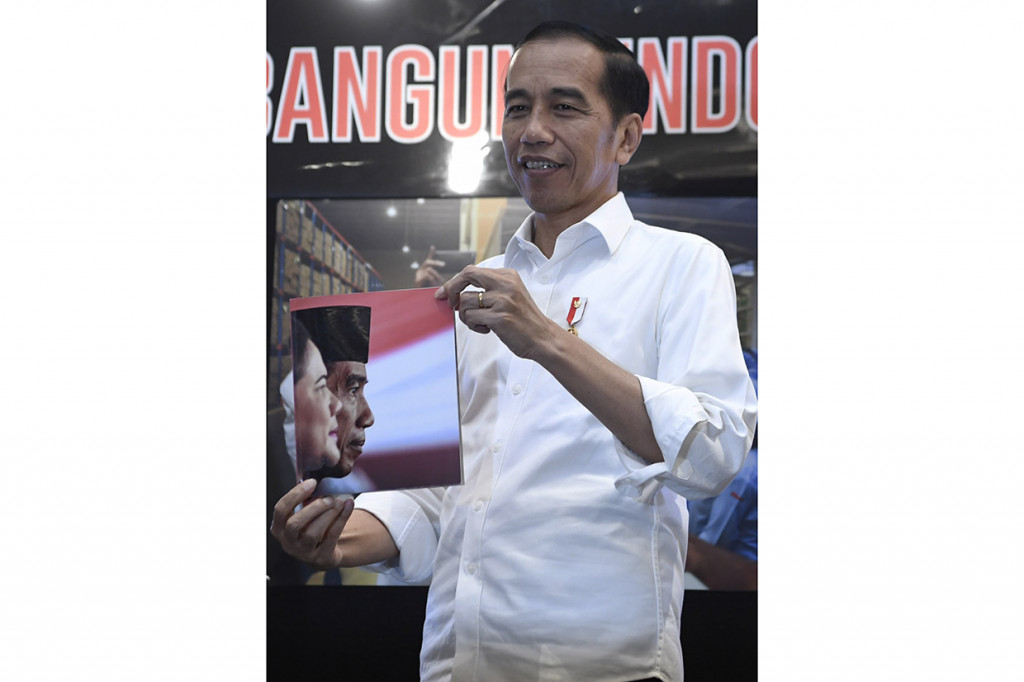 Presiden Joko Widodo menunjukkan buku fotografi Membangun Indonesia saat mengunjungi pameran di Atrium Neo Soho Mall, Jakarta.