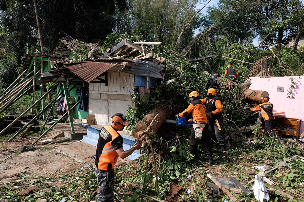 Tim SAR bersama relawan menyingkirkan batang pohon yang tumbang menimpa rumah warga di Beji, Petirejo, Ngadirejo, Temanggung, Jawa Tengah, Sabtu, 23 November 2019. 