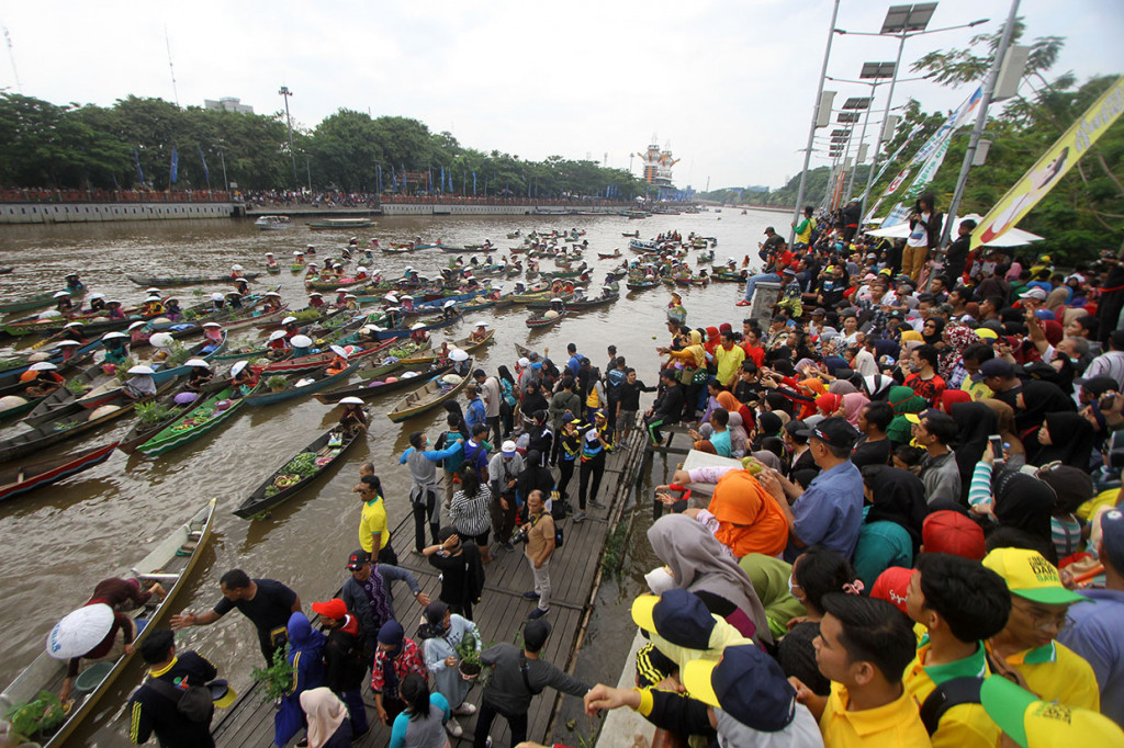 Sejumlah pedagang pasar terapung membagikan sayur dan buah di sungai Martapura, Banjarmasin, Kalimantan Selatan.