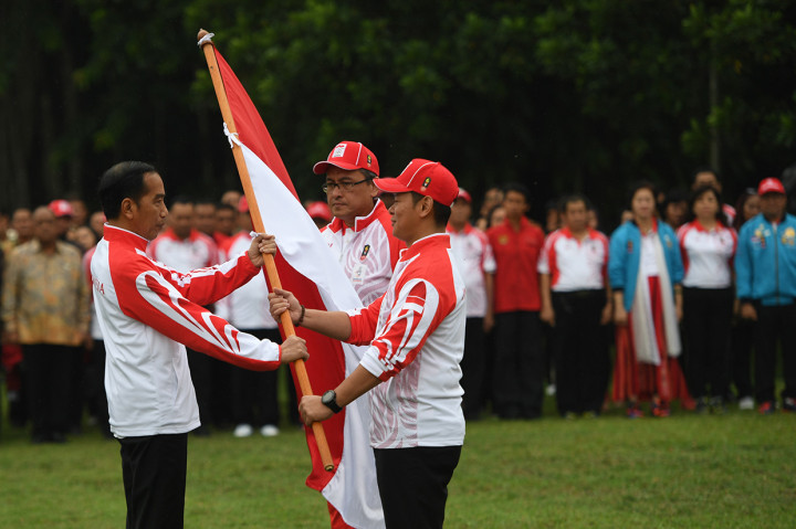 Presiden Joko Widodo (kiri) menyerahkan bendera kepada Ketua Komite Olimpiade Indonesia (KOI) Raja Sapta Oktohari (kanan) disaksikan Ketua Kontingen Indonesia Harry Warganegara (tengah) saat pelepasan atlet untuk SEA Games 2019 di Istana Bogor, Jawa Barat.
