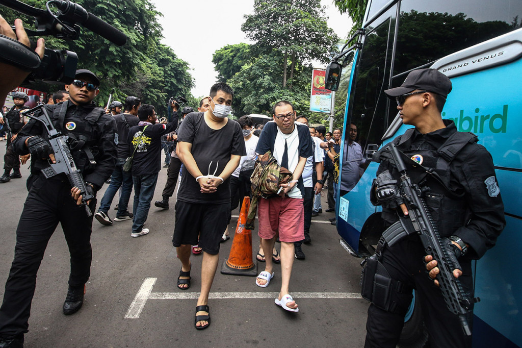 Sejumlah tersangka yang merupakan Warga Negara Asing (WNA) berjalan menaiki bus saat diserahkan ke pihak imigrasi di Polda Metro Jaya, Jakarta.