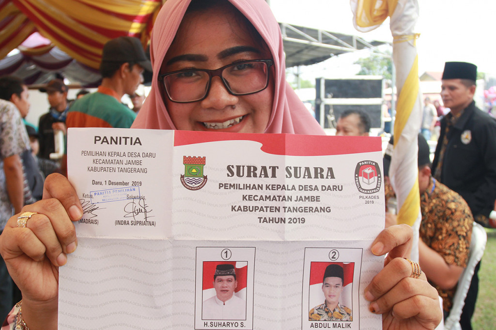 Seorang warga menunjukkan surat suara pemilihan Kepala Desa yang calonnya merupakan anak dan bapak yakni Suharyo (bapak) dan Abdul Malik (anak) di Desa Daru, Kabupaten Tangerang, Banten.