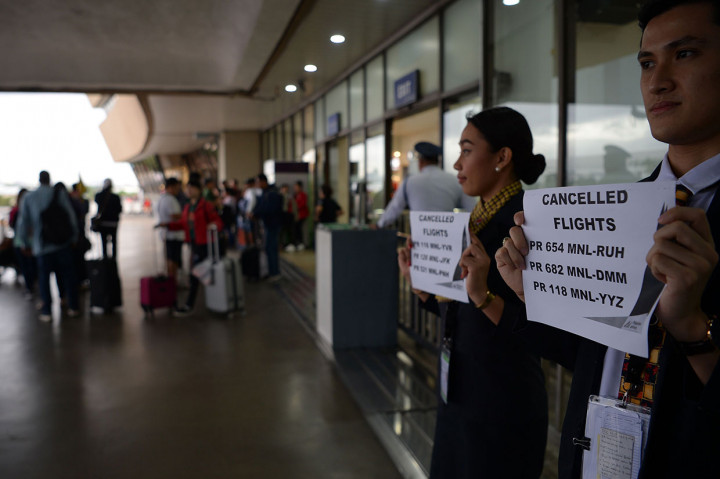 Staf maskapai penerbangan memegang plakat yang mengumumkan pembatalan penerbangan di terminal bandara internasional Manila, Selasa, 3 Desember 2019.