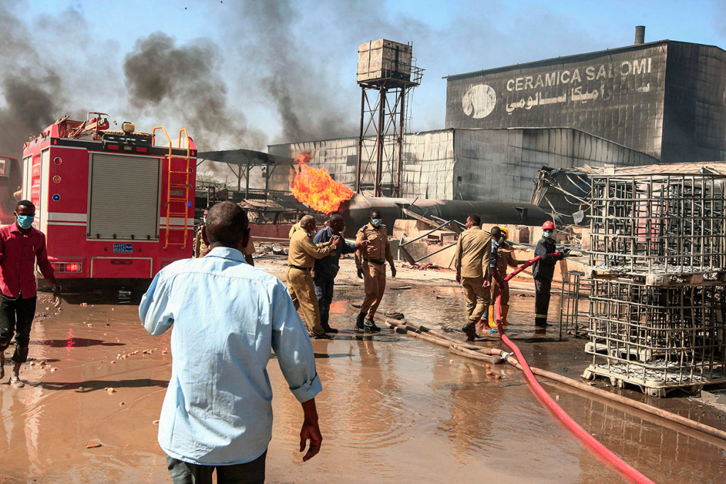 Asap tebal hitam mengepul ke langit setelah kobaran api meletus di sebuah  pabrik keramik di zona industri Khartoum utara. Beberapa mobil yang diparkir di kompleks pabrik juga terbakar.