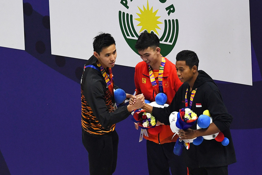 Perenang Indonesia Prawira Aflah (kanan) berjabat tangan dengan perenang Vietnam Nguyen Huu Kim Son (tengah) dan perenang Malaysia Khiew Hoe Yean usai upacara penganugerahan medali juara Renang Gaya Bebas 400 meter Putra SEA Games ke-30 di New Clark City Aquatic Center, Filipina.