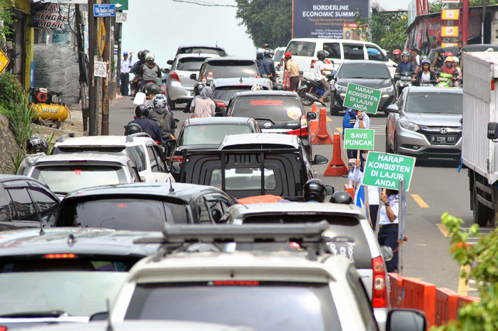Petugas Badan Pengelola Transportasi Jabodetabek (BPTJ) membawa papan pengumuman saat uji coba kedua sistem kanalisasi dua lajur arah turun dan satu lajur arah naik (2-1) di jalur Puncak, Ciawi, Kabupaten Bogor, Jawa Barat, Sabtu, 7 Desember 2019.