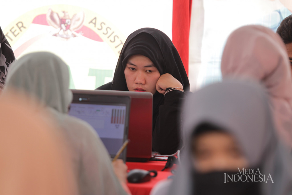 Peserta mengerjakan soal-soal saat mengikuti simulasi ujian penerimaan Calon Pegawai Negeri Sipil (CPNS) 2019/2020 yang diselenggarakan oleh Badan Kepegawaian Negara (BKN) di halaman parkir pusat perbelanjaan Sarinah, Jakarta.