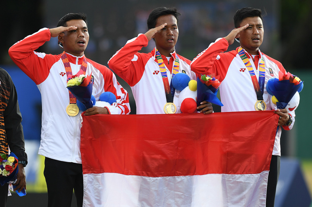 Tim panahan putra Indonesia Hendra Purnama (kiri), Arif Dwi Pangestu (tengah) dan Riau Ega Salsabilla memberi hormat kepada Bendera Merah Putih dalam penganugerahan medali juara Panahan Recurve Tim Putra SEA Games ke-30 di Lapangan Parade Ground Clark Freeport, Filipina.